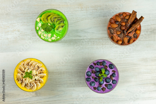 Smoothies or puddings with kiwi, bannas, blueberries and chocolate with almonds and hazelnuts in a crystal bowls.Top view image