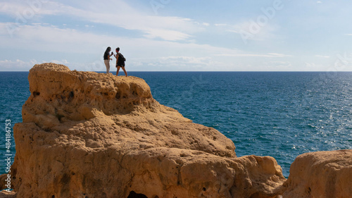 Beautiful landscape with two girls on the cliff at the ocean