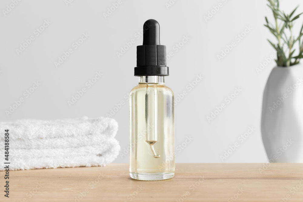 Dropper bottle mockup with a towel and a rosemary on the wooden table. Dropper bottle mockup with a towel and a rosemary on the wooden table.