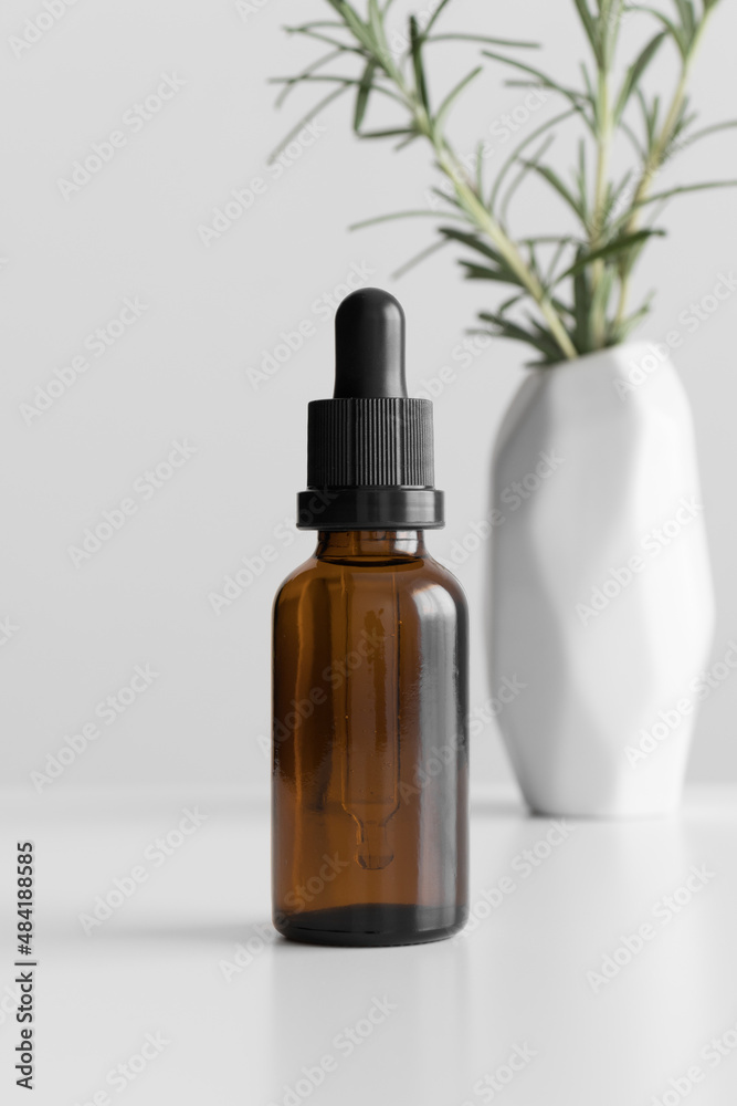 Dropper bottle mockup with a rosemary on the white table.