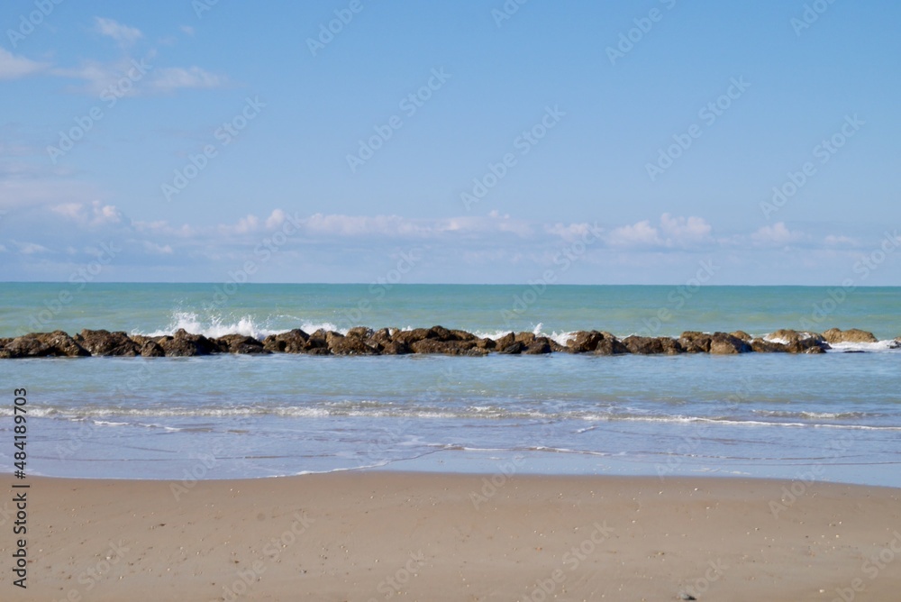 Sandy beach with wave breakers and blue sky. Room for copy space. Sciacca, Sicily, Italy.