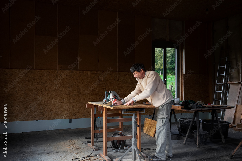 Carpenter installing thermal insulation inside a building, wood fiber boards and OSB
