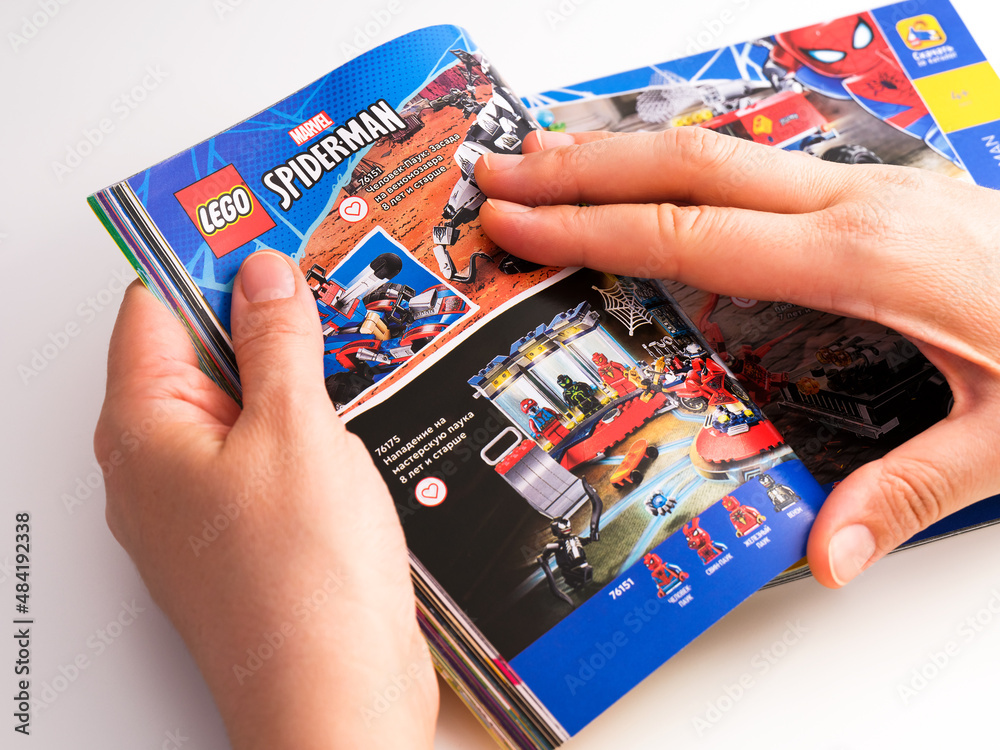 Obraz premium Tambov, Russian Federation - December 21, 2021 Woman browsing Lego catalog on a page with Lego Spider-Man sets.