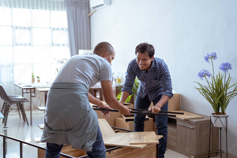two male woodworker assembling new furniture together two male woodworker assembling new furniture together