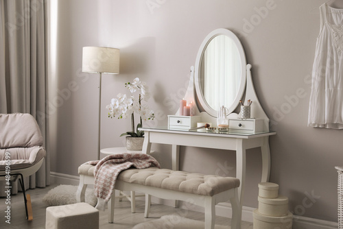 Wooden dressing table with decorative elements and makeup products in room. Interior design © New Africa
