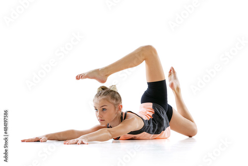 Portrait of little beautiful rhythmic gymnastics artist, kid at sport training isolated on white studio background. Flexibility, health, activity