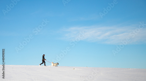 man and his happy white dog enjoying winter snow outdoors on sunny day