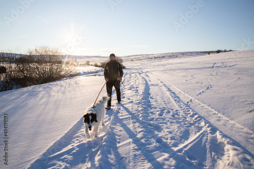 man and his happy white dog enjoying winter snow outdoors on sunny day