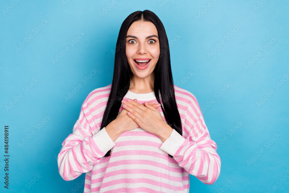 Photo of young lovely girl arms on chest unexpected news thankful isolated over blue color background Photo of young lovely girl arms on chest unexpected news thankful isolated over blue color background