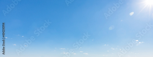 Blauer Himmel mit Sonnenreflex und Sonnenstrahlen
