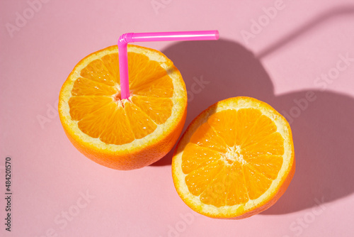 The concept of fresh natural orange juice. Sliced orange on a pink background. refreshing drink