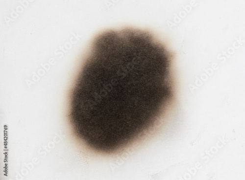 Paper burn black  stain isolated over the white background. Round paper burn mark close up