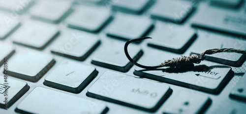 phishing and cyber crime concept. fishing hook on computer keyboard. copy space photo