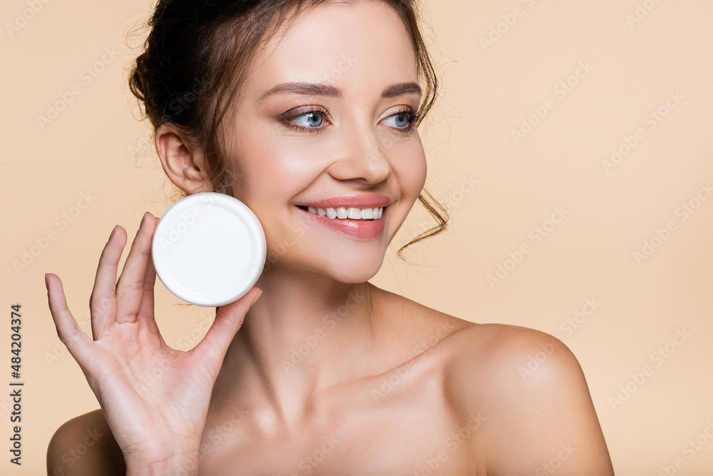 Positive model with naked shoulders holding cosmetic cream isolated on beige. Positive model with naked shoulders holding cosmetic cream isolated on beige.