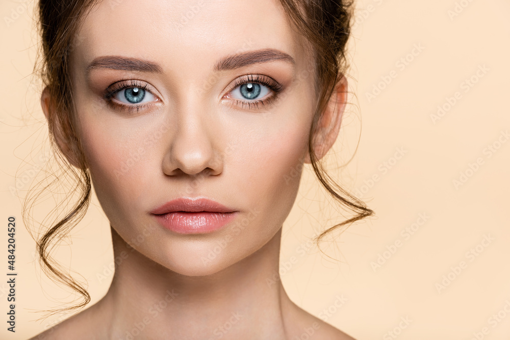 Young woman with visage looking at camera isolated on beige. Young woman with visage looking at camera isolated on beige.
