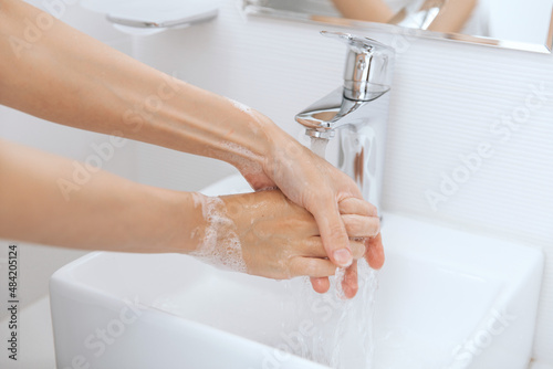 Washing hands under the flowing water tap. Washing hands rubbing with soap for corona virus prevention, hygiene to stop spreading corona virus in or public wash room. Hygiene concept hand detail