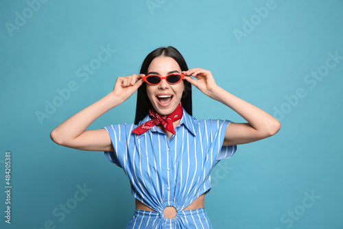 Fashionable young woman in stylish outfit with bandana on light blue background © New Africa