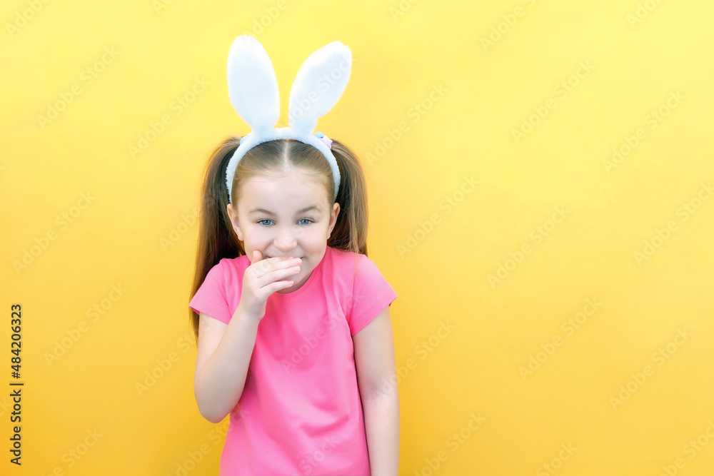 cheerful girl with rabbit ears on her head on a yellow background. Funny crazy happy child. Easter child. Preparation for the Easter holiday. promotional items. copy space cheerful girl with rabbit ears on her head on a yellow background. Funny crazy happy child. Easter child. Preparation for the Easter holiday. promotional items. copy space