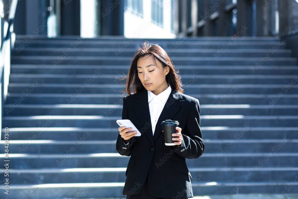 A beautiful Asian student uses the phone near the university campus