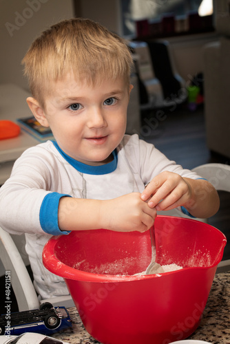 Little boy takes a break from playing cars to help dad mix ingredients for apple pie