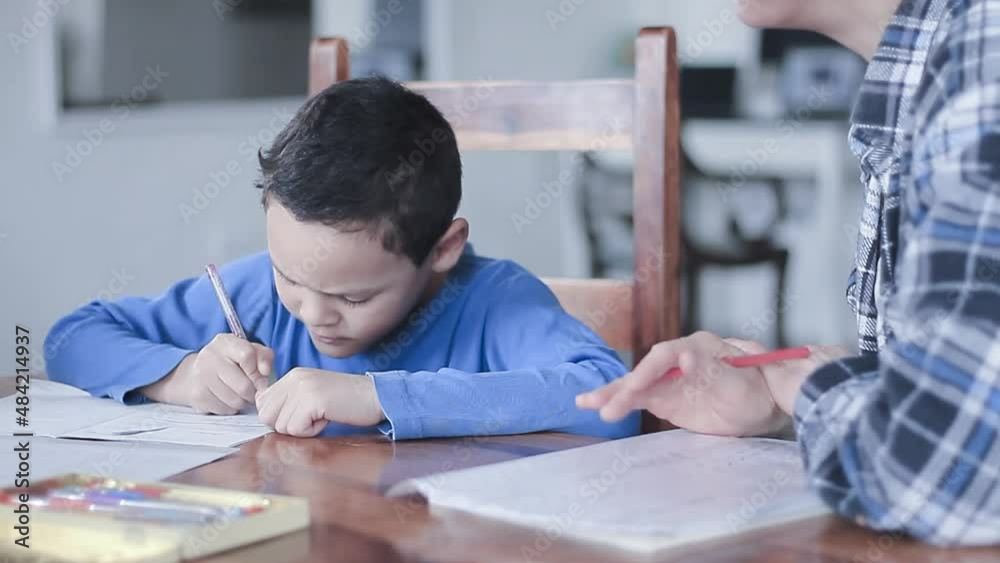 boy child doing homework learning at home with mother sitting at a table stock video boy child doing homework learning at home with mother sitting at a table stock video