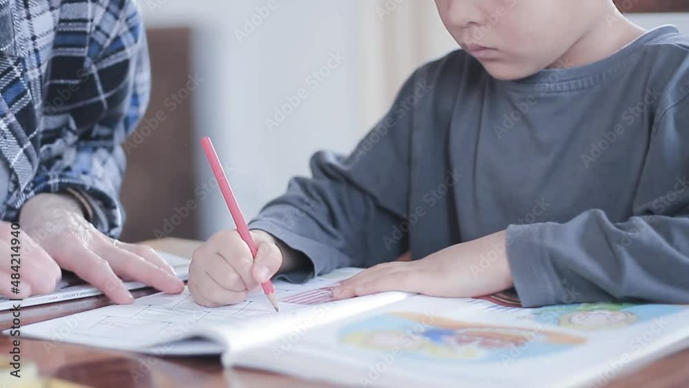 boy child doing homework learning at home with mother sitting at a table stock video boy child doing homework learning at home with mother sitting at a table stock video
