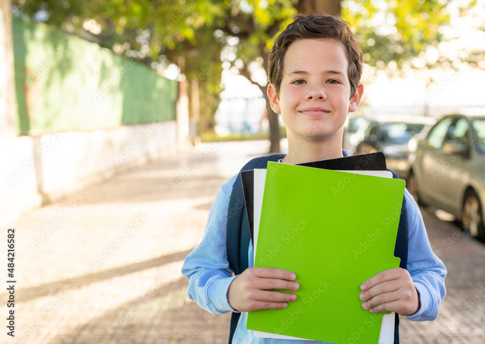Portrait of cute boy with backpack holding notebooks outside of school. Portrait of cute boy with backpack holding notebooks outside of school.