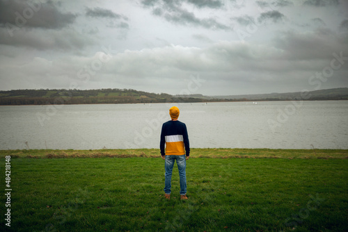 Person looking to the lake with a yellow hat.