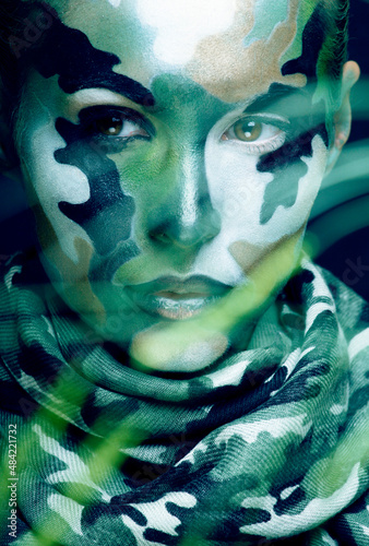Beautiful young fashion woman with military style clothing and face paint make-up, khaki colors, halloween celebration close up, green pattern