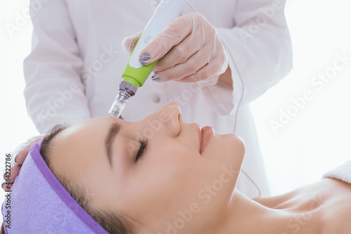 Fractional mesotherapy.A young beautiful woman in the cosmetologist’s office receives fractional mesotherapy for her face. Facial skin rejuvenation. Acne treatment. Hardware cosmetology. Beautician.