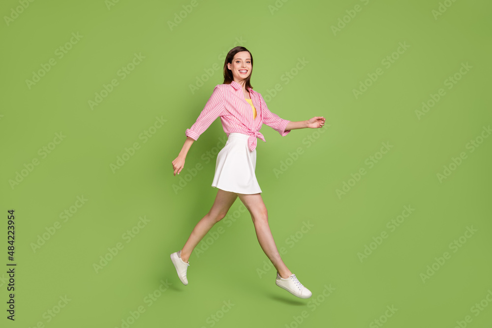 Full size profile side of young lady jumping traveling energetic lifestyle carefree isolated on green color background Full size profile side of young lady jumping traveling energetic lifestyle carefree isolated on green color background