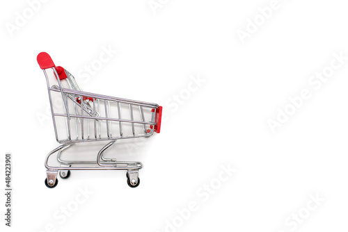A small trolley for transporting groceries in a supermarket on a white background. The concept of transportation or purchase of goods with free space for advertising or text © halcon1