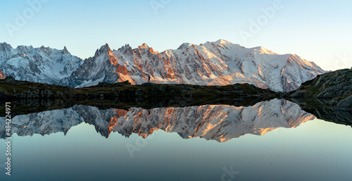 Hiker admiring Dent du Geant and Mont Blanc covered with snow reflected in Lacs des Cheserys at sunset, Haute Savoie, French Alps, France