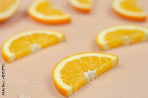 Orange slice on a beige background with water drops  selective focus