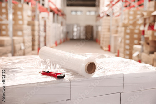 Roll of stretch wrap and utility knife on boxes in warehouse
