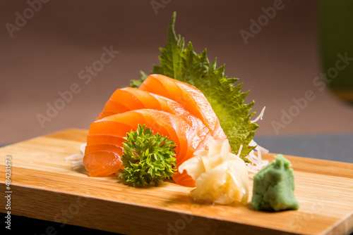 Sashimi japanese food, pieces of tuna, salmon in a wooden background. Fish slices. Front view with Copy Space.
