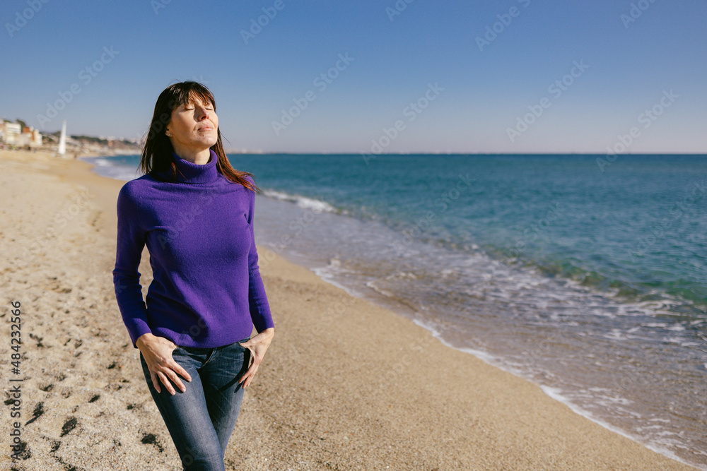 Beautiful mature woman relaxing breathing fresh air on a sunny winter day at the beach Beautiful mature woman relaxing breathing fresh air on a sunny winter day at the beach
