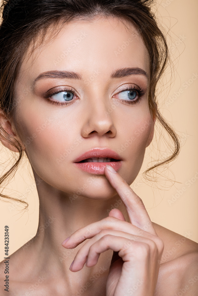 Portrait of woman with naked shoulders touching lip isolated on beige. Portrait of woman with naked shoulders touching lip isolated on beige.