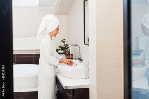 Photos Attractive middle-aged woman washes her face in the bathroom in the morning