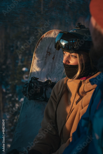 Portrait Beautiful young girl on a ski resort against the backdrop of snowy mountains in a gondola cabin. Lift or elevator to the top of the mountain. Dressed in winter clothes for snowboarding.