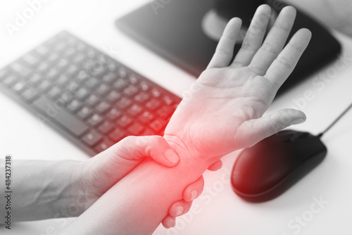 Woman working in office with a carpal tunnel syndrome or wrist joint inflammation