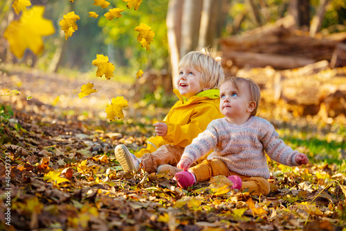 Two siblings boy and girl throw leaves in forest