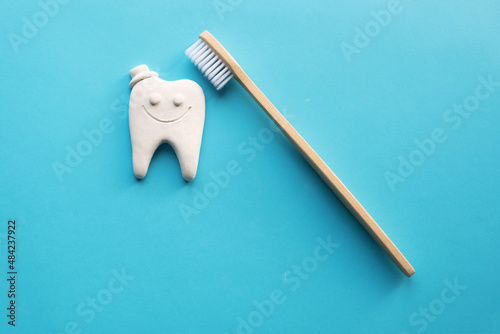 Bamboo toothbrush and white tooth on a blue background. Flat layout. Place for an inscription. Ecoproduct photo