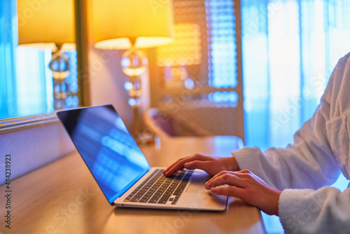 Freelancer using laptop for distance online working in a hotel room