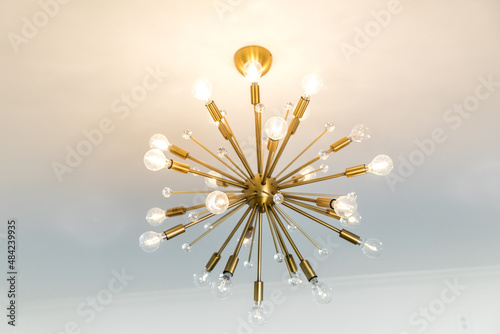 Retro starburst warm gold lighting fixture against a white wall