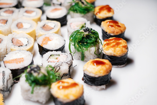 Japanese food restaurant. Sushi roll set maki california at white background, above view decorated with leaves flat lay side view.