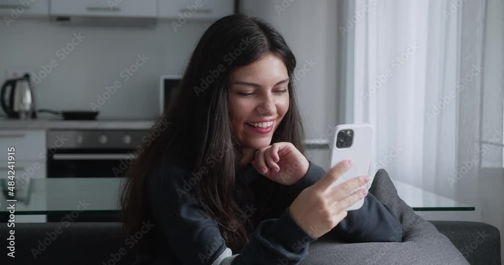 Woman relaxing on sofa texting using smartphone browsing online playing mobile games enjoying sharing messages on social media Woman relaxing on sofa texting using smartphone browsing online playing mobile games enjoying sharing messages on social media