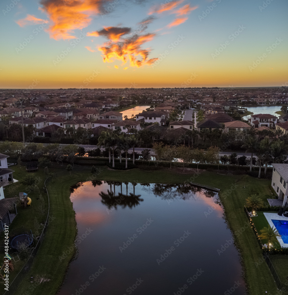Sunset over water reflecting palm trees and houses in Parkland, Florida