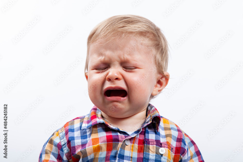 Niño llorando. Niño con camisa con cuadros sobre fondo blanco llorando. Niño llorando. Niño con camisa con cuadros sobre fondo blanco llorando.