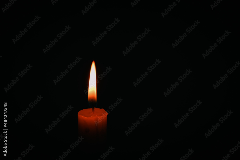 Candle flame on black background. Single lit candle with quite flame. Dramatic burning candle flame on a black background with copy space Candle flame on black background. Single lit candle with quite flame. Dramatic burning candle flame on a black background with copy space
